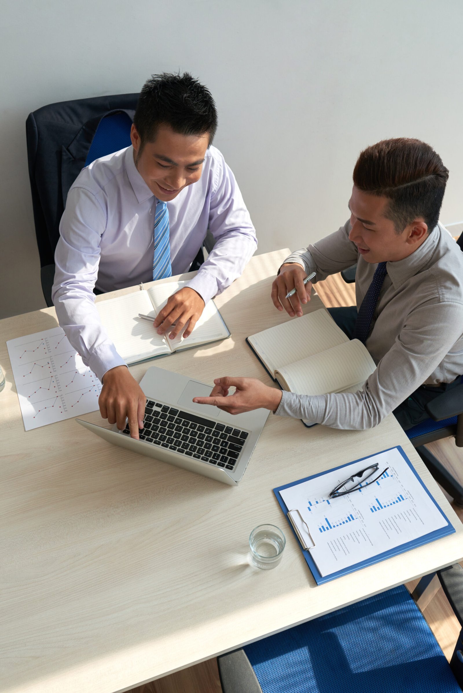 Businessman showing something interesting on laptop screen to his coworker at the meeting